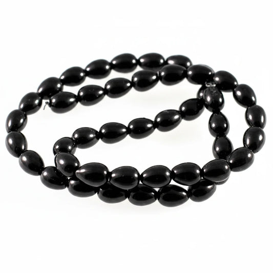 A strand of glossy black teardrop-shaped beads, likely onyx or black jasper, arranged in a loop on a plain white background.