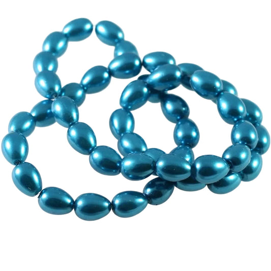 Metallic blue teardrop-shaped beads arranged in a loose coil on a plain white background.
