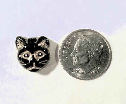 Small silver cat-shaped object next to a dime coin on a white background