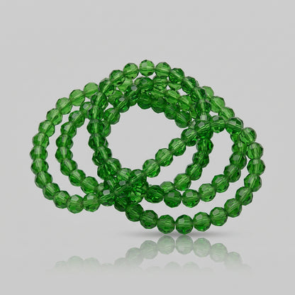 Green faceted glass beads arranged in loops on a plain white background.