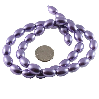 Purple metallic oval beads on a string, shown with a US quarter coin and a ruler for scale on a white background.