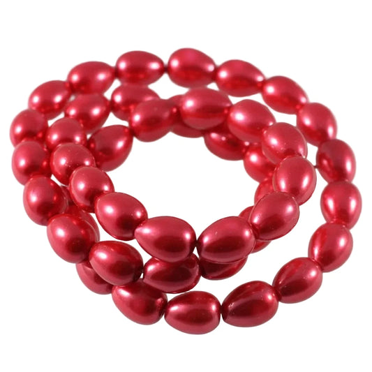 A coiled strand of shiny metallic red oval beads on a plain white background.