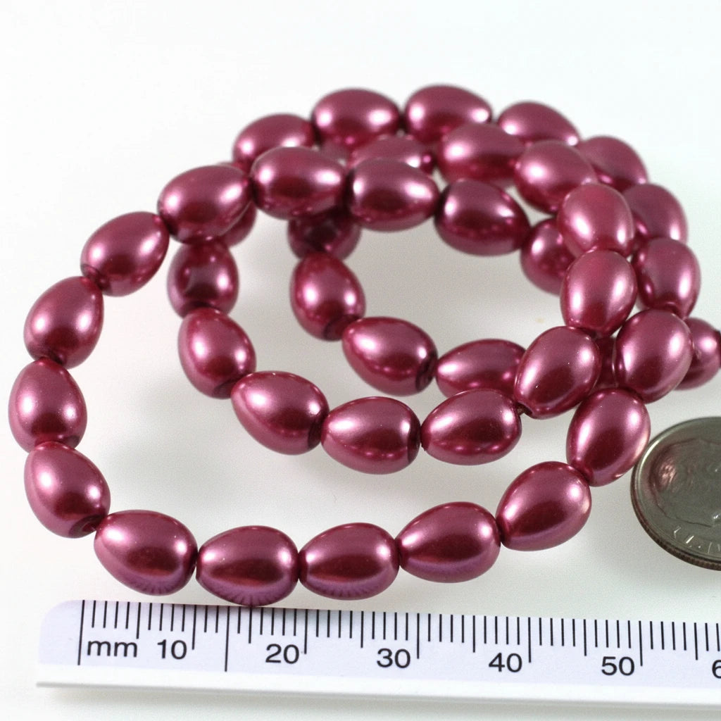 A strand of glossy, oval-shaped beads in a deep berry purple color, shown next to a US quarter coin and a millimeter ruler for scale on a white background.