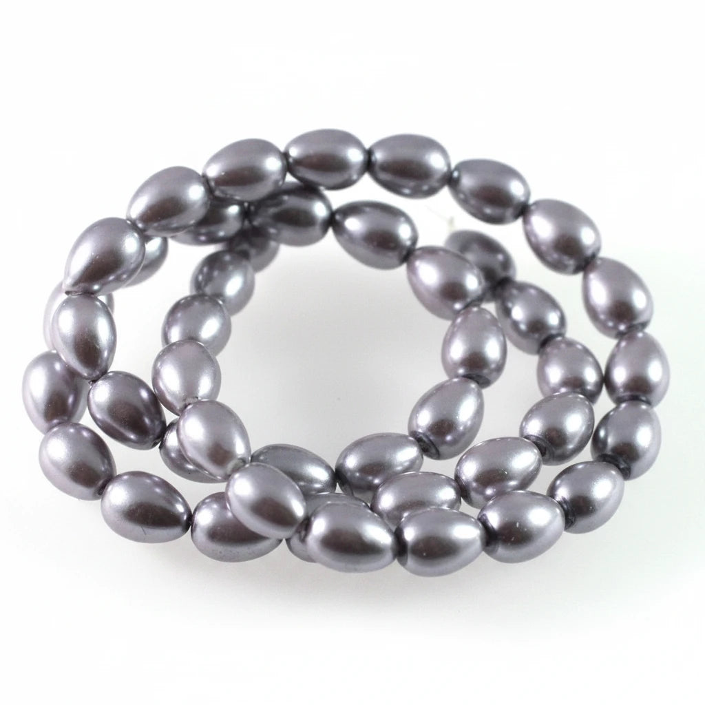 A coiled strand of dark gray, teardrop-shaped freshwater pearl beads on a plain white background.