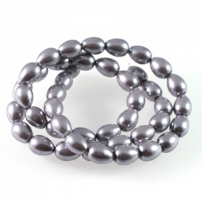 A coiled strand of dark gray, teardrop-shaped freshwater pearl beads on a plain white background.