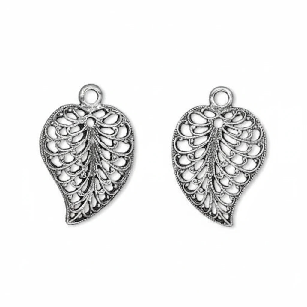 A pair of silver-toned filigree leaf-shaped charms with hanging loops, shown on a plain white background.