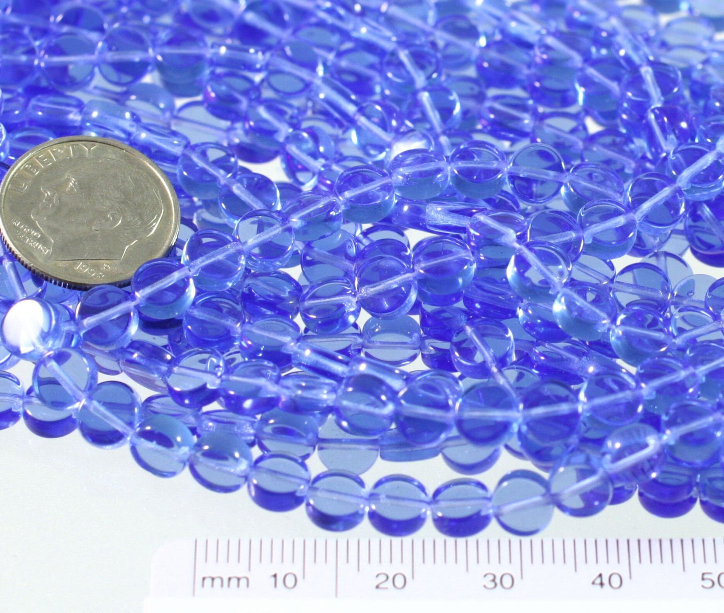 Blue glass beads with a dime and ruler for size reference