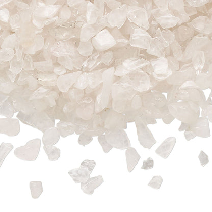 White crystal salt or bath salts granules piled on a white background, with a few pieces scattered in front.