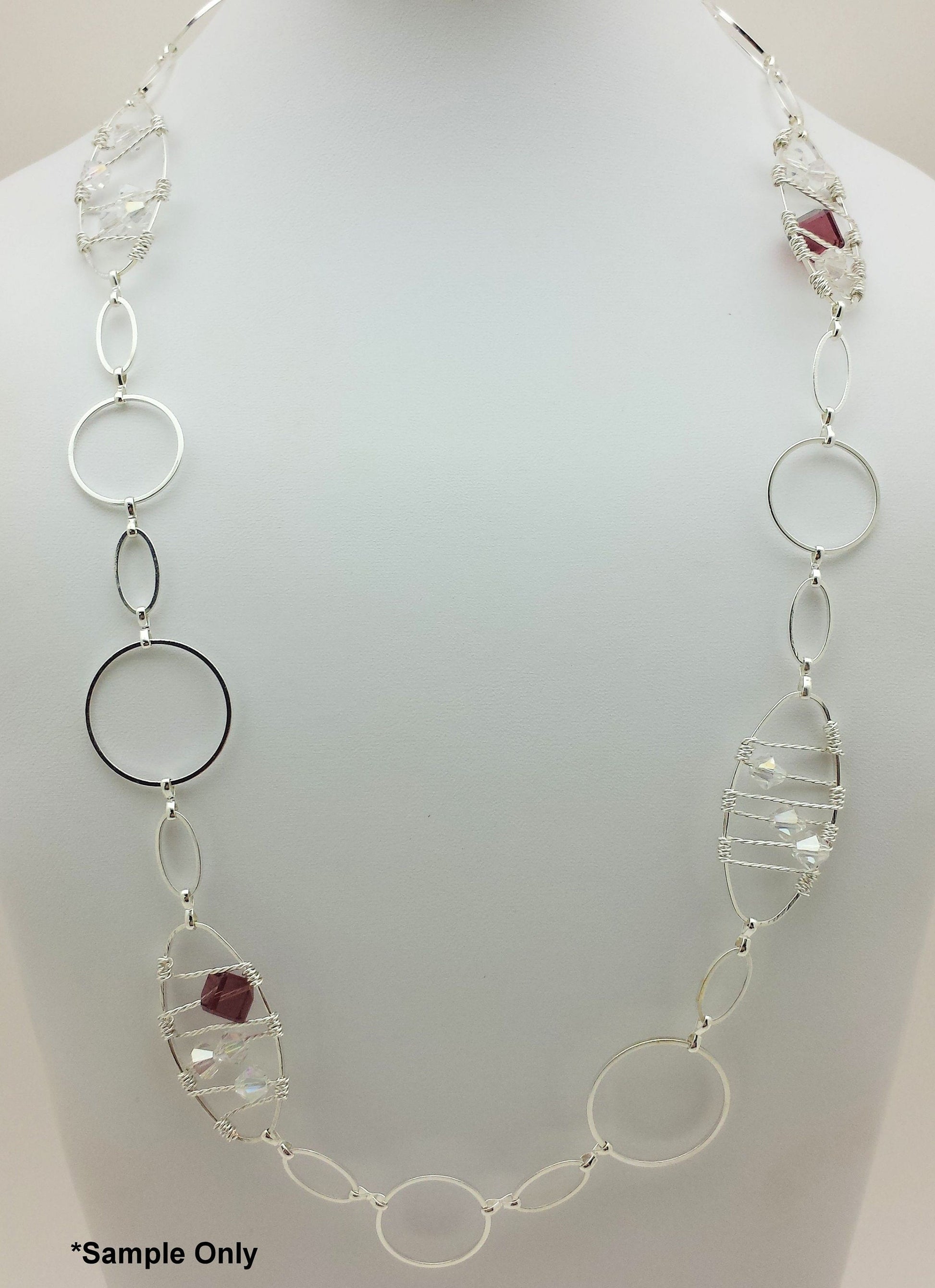 Silver necklace with circular and leaf-shaped links on a mannequin.