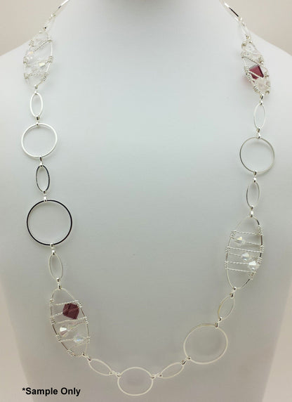 Silver necklace with circular and leaf-shaped links on a mannequin.