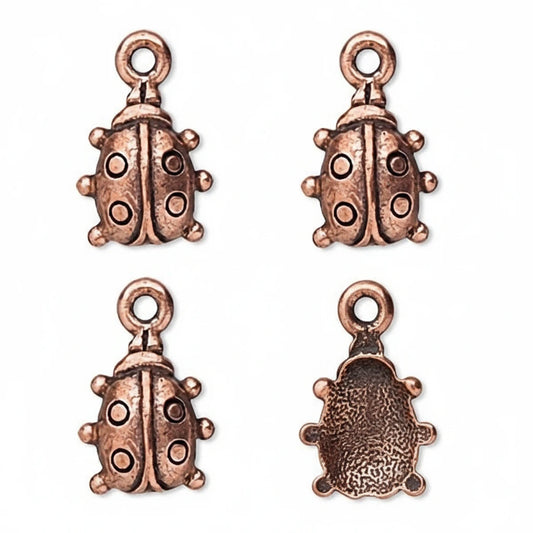 Four antique bronze ladybug charms with loop tops, shown on a plain white background, with one charm displayed from the back.