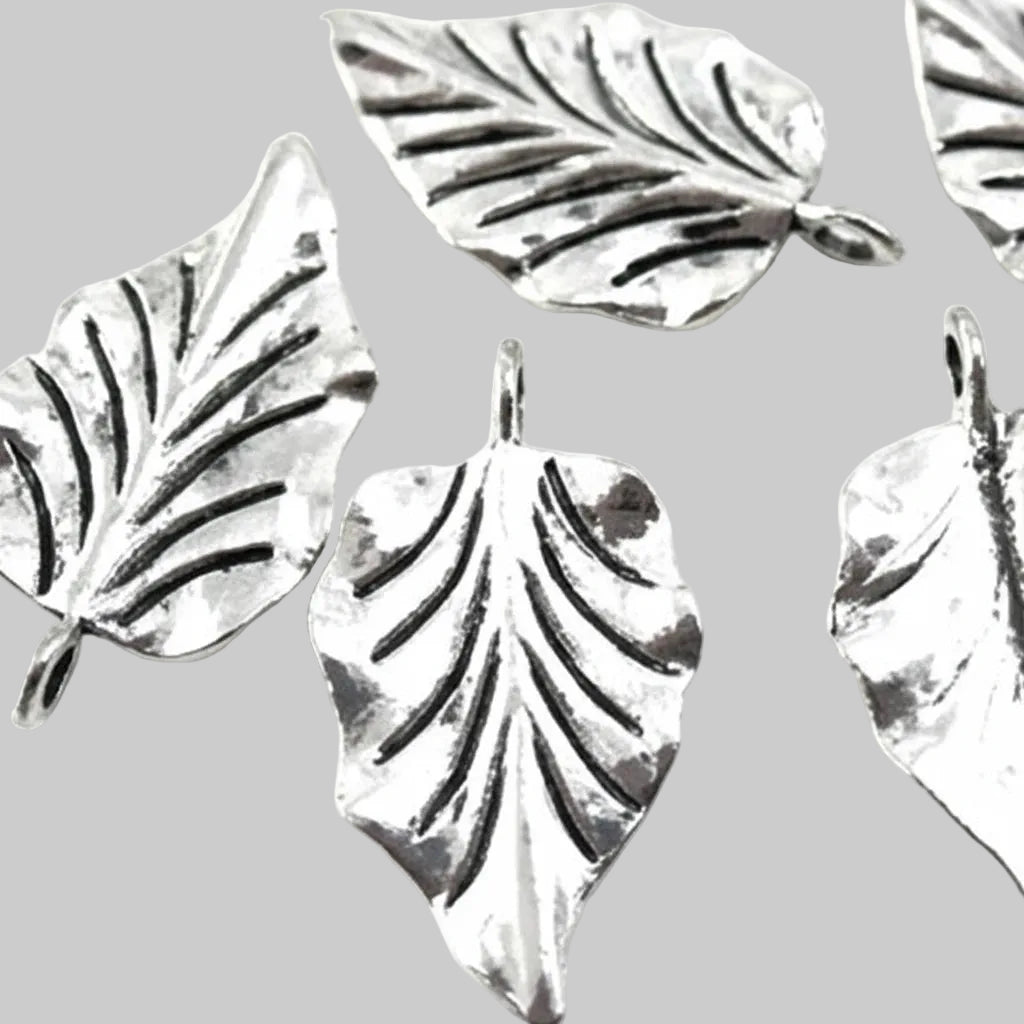 Five silver-toned leaf-shaped jewelry charms with textured leaf veins and hanging loops, arranged on a light gray background.