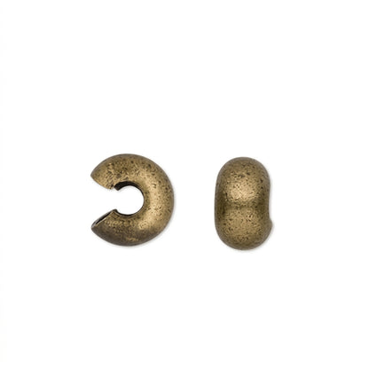 Two small CRIMP bead COVERS in an antique bronze finish, shown on a plain white background.