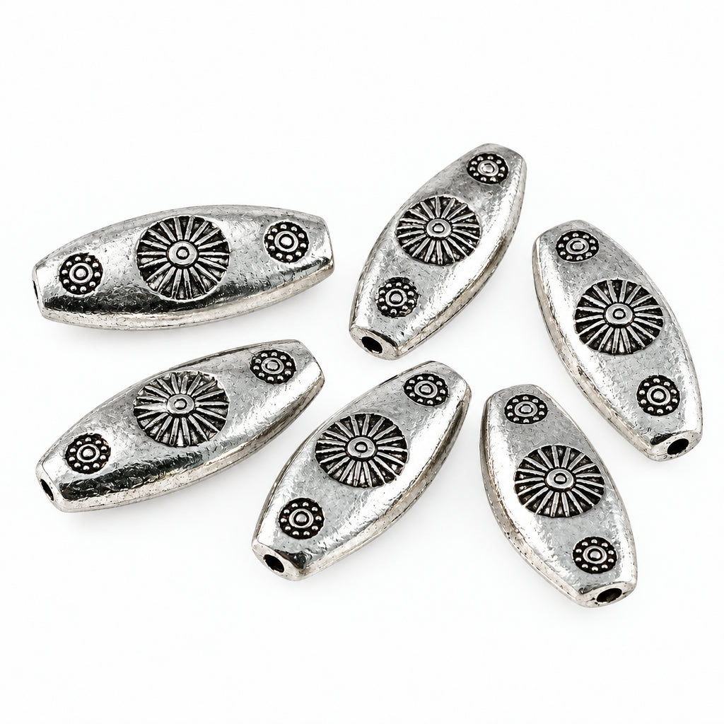 Five silver-toned metal spacers with embossed sunburst and floral designs, arranged on a plain white background.