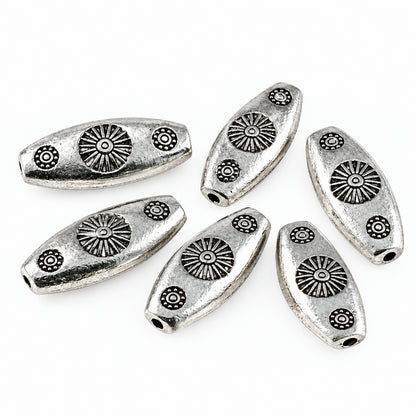 Five silver-toned metal spacers with embossed sunburst and floral designs, arranged on a plain white background.
