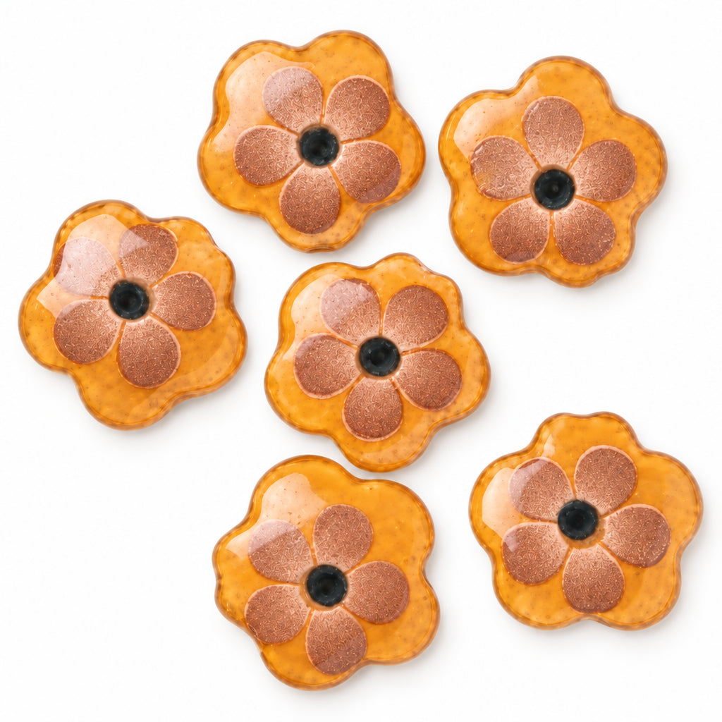 Five orange flower-shaped beads with metallic bronze petals and dark centers, arranged on a plain white background.