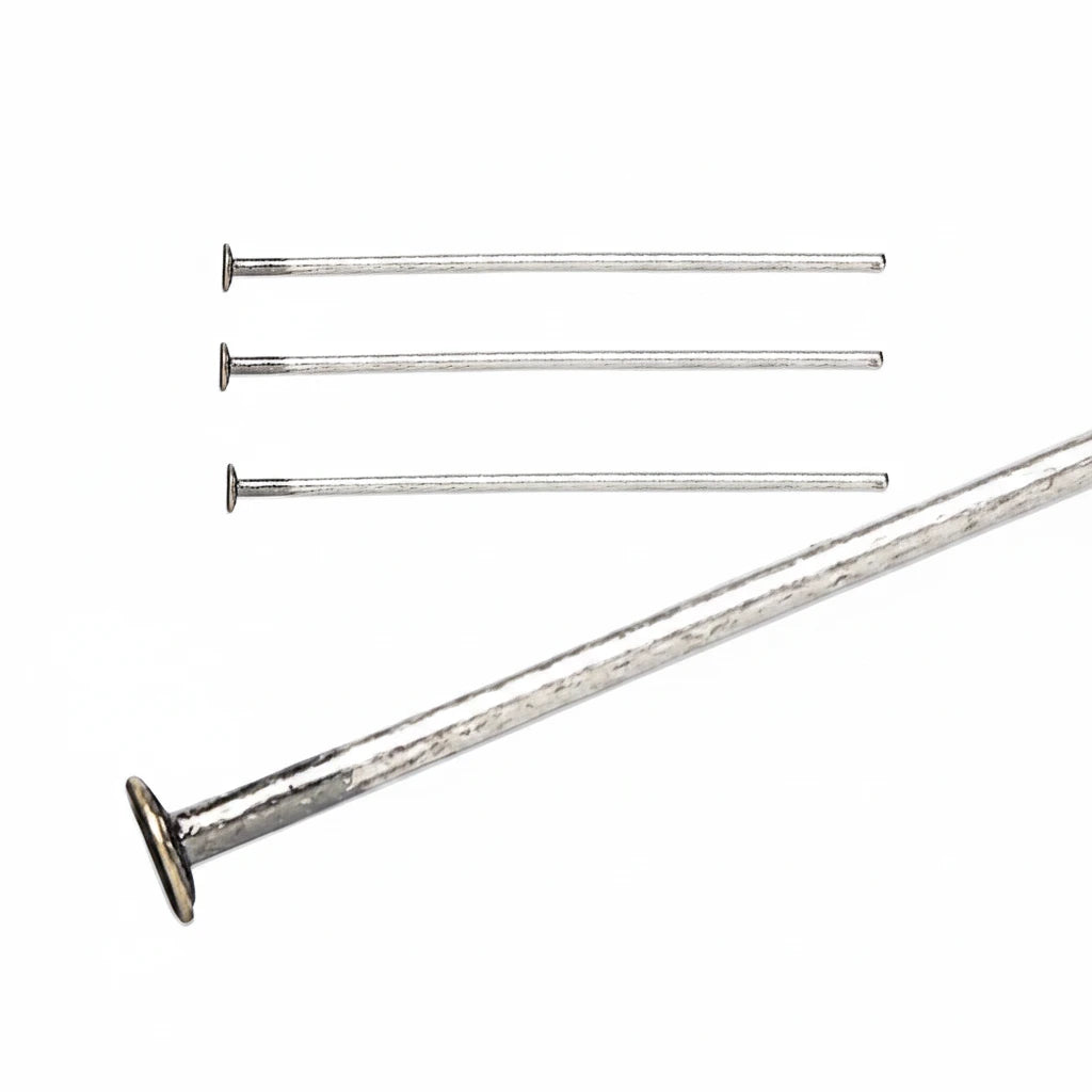 Four silver metal nails with flat heads, shown on a plain white background, with one nail enlarged in the foreground.