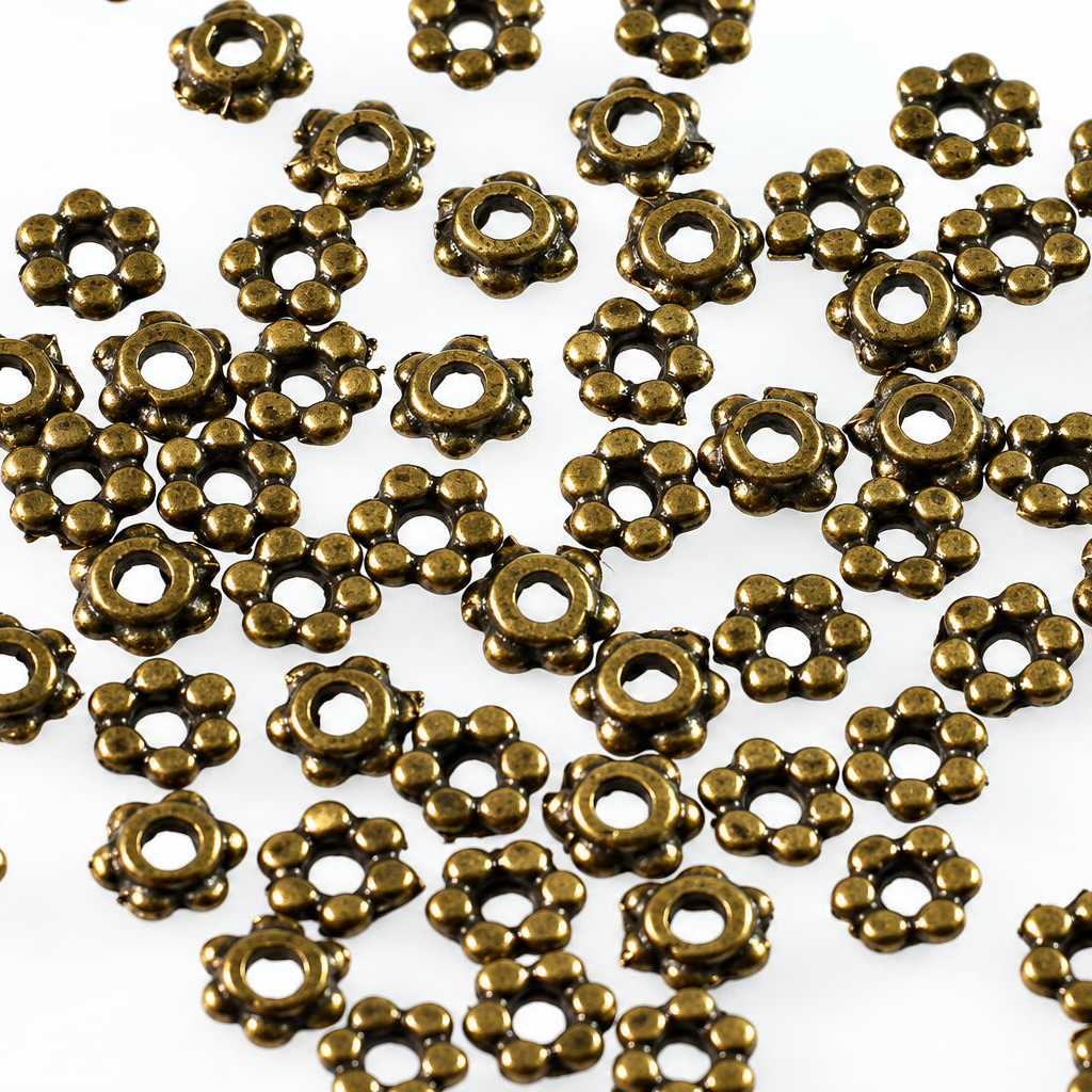 A pile of small metallic flower-shaped beads in an antique bronze finish, scattered on a plain white background.