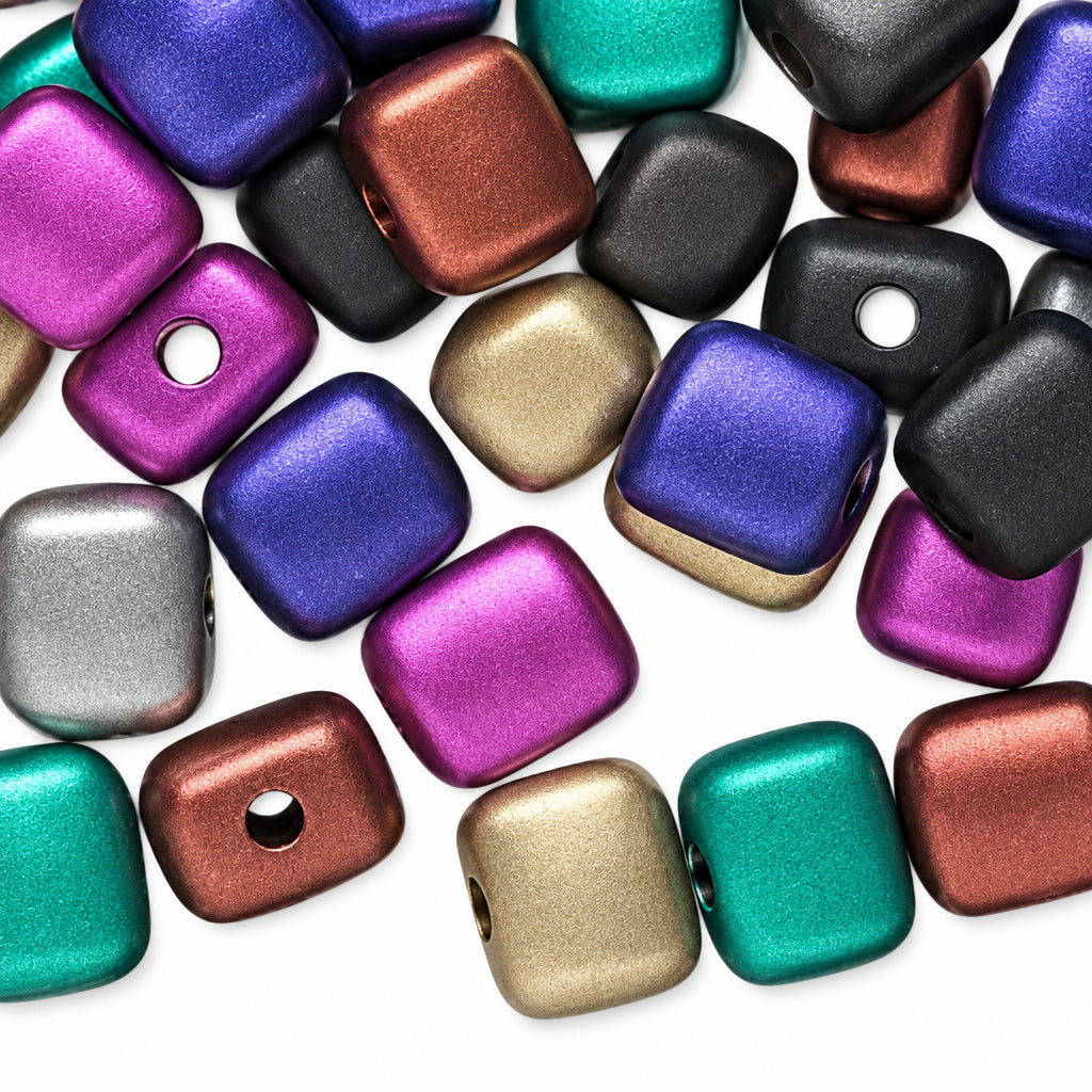 A pile of metallic square beads with rounded corners and holes, shown in multiple colors including purple, green, bronze, silver, and black on a white background.