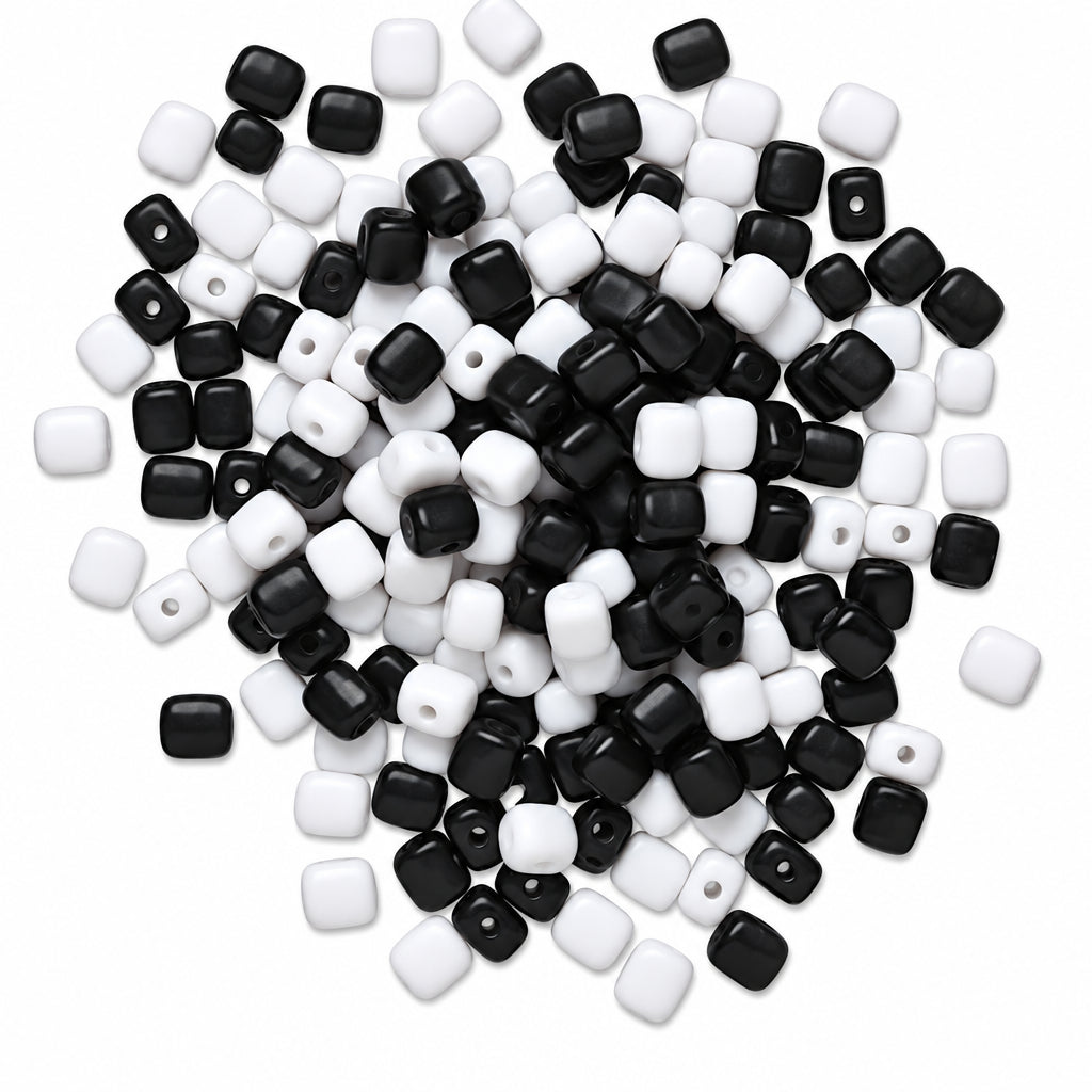 A pile of small square beads in black and white, photographed on a plain white background.