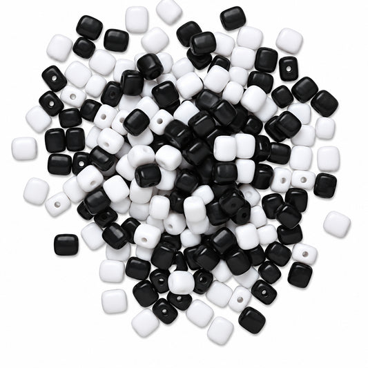 A pile of small square beads in black and white, photographed on a plain white background.