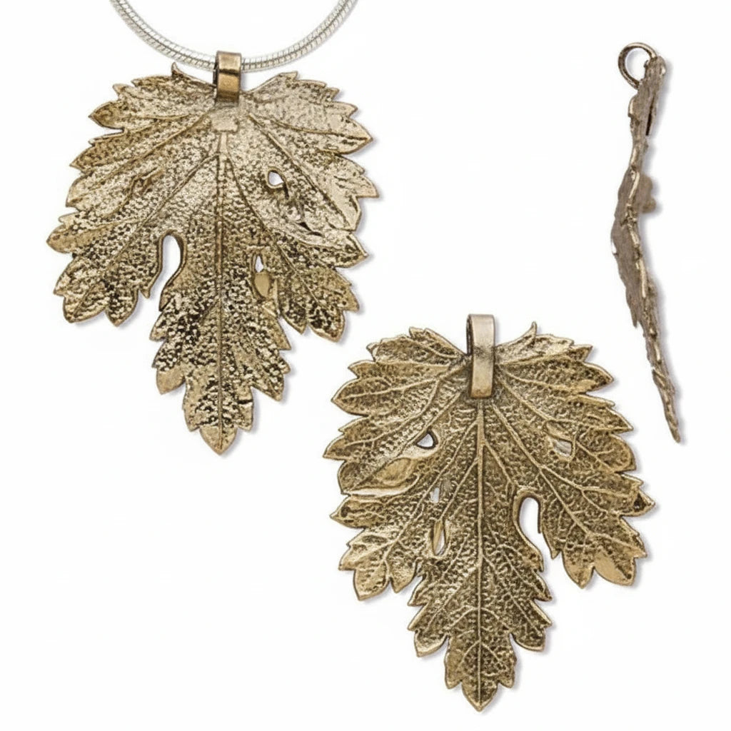 A set of textured metallic leaf-shaped jewelry pieces on a plain white background, including a necklace pendant with a chain, a larger matching pendant, and a smaller dangling charm.