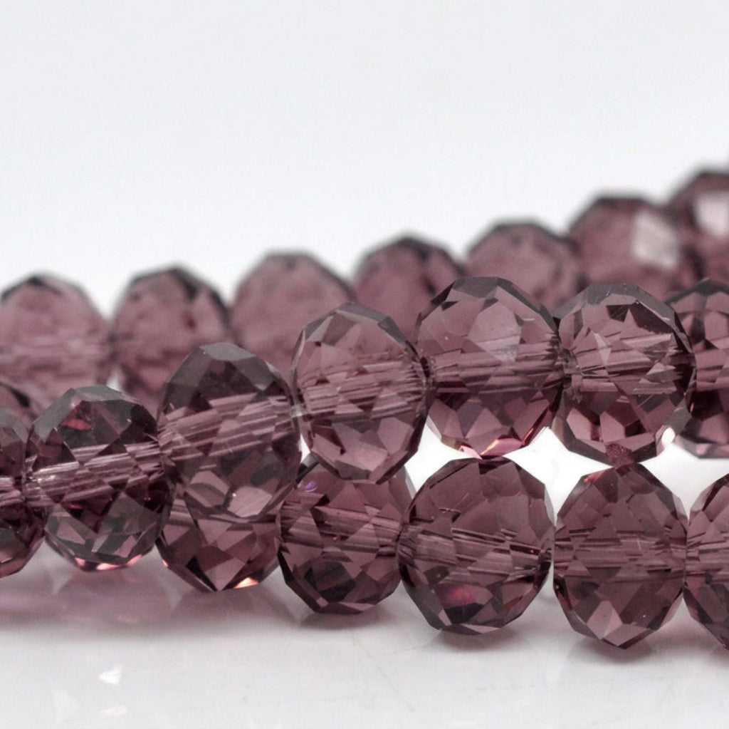 Faceted round beads in a smoky translucent purple color, arranged in two rows on a white background.