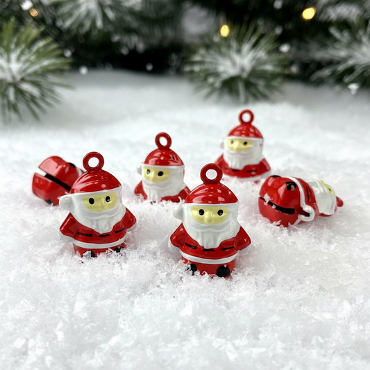 Five small red and white Santa Claus jingle bell ornaments arranged in white faux snow, with blurred evergreen branches and warm string lights in the background.
