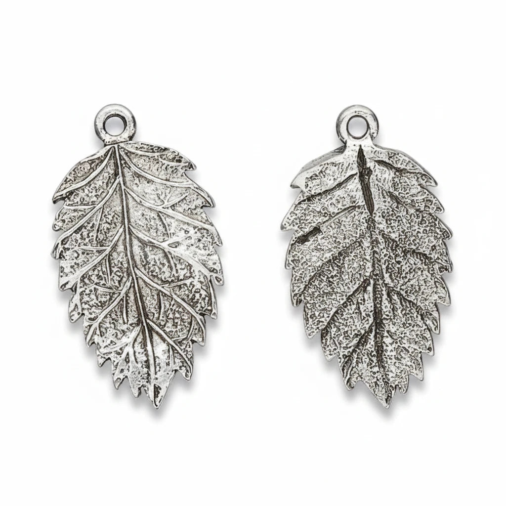 Two silver-toned leaf-shaped jewelry charms with textured engravings and top loop attachments, shown on a plain white background.