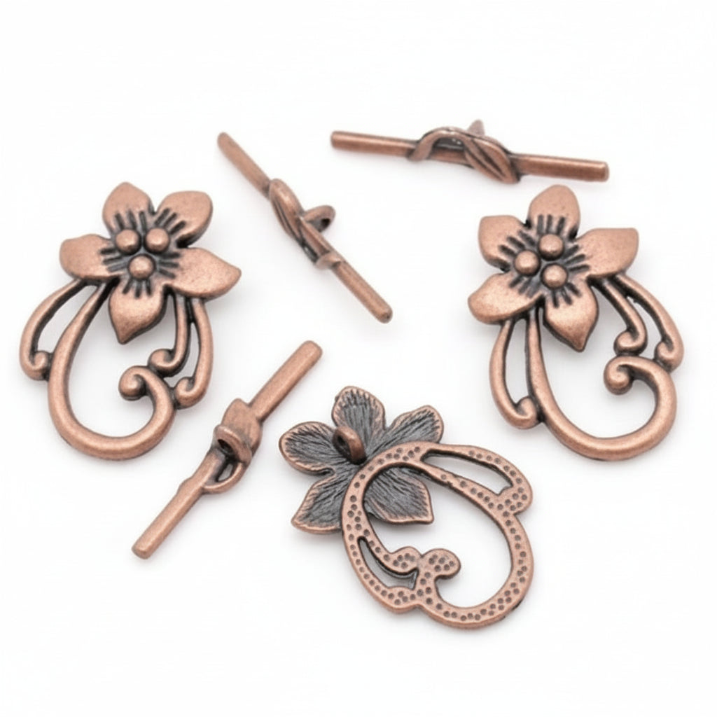 A set of antique bronze jewelry findings, including two flower-shaped toggle clasp components, two toggle switches, and one decorative floral ring pull, displayed on a clean white background.
