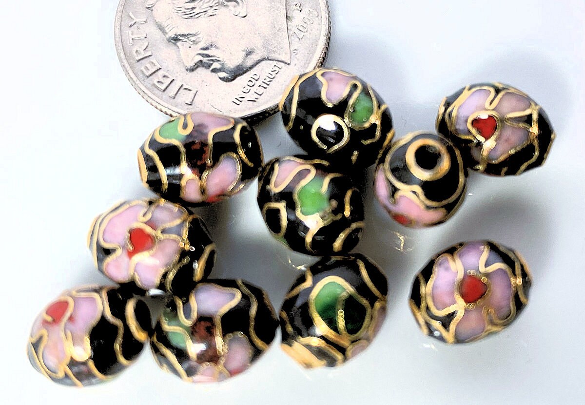 Decorative beads with floral patterns on a white background, next to a dime for scale.