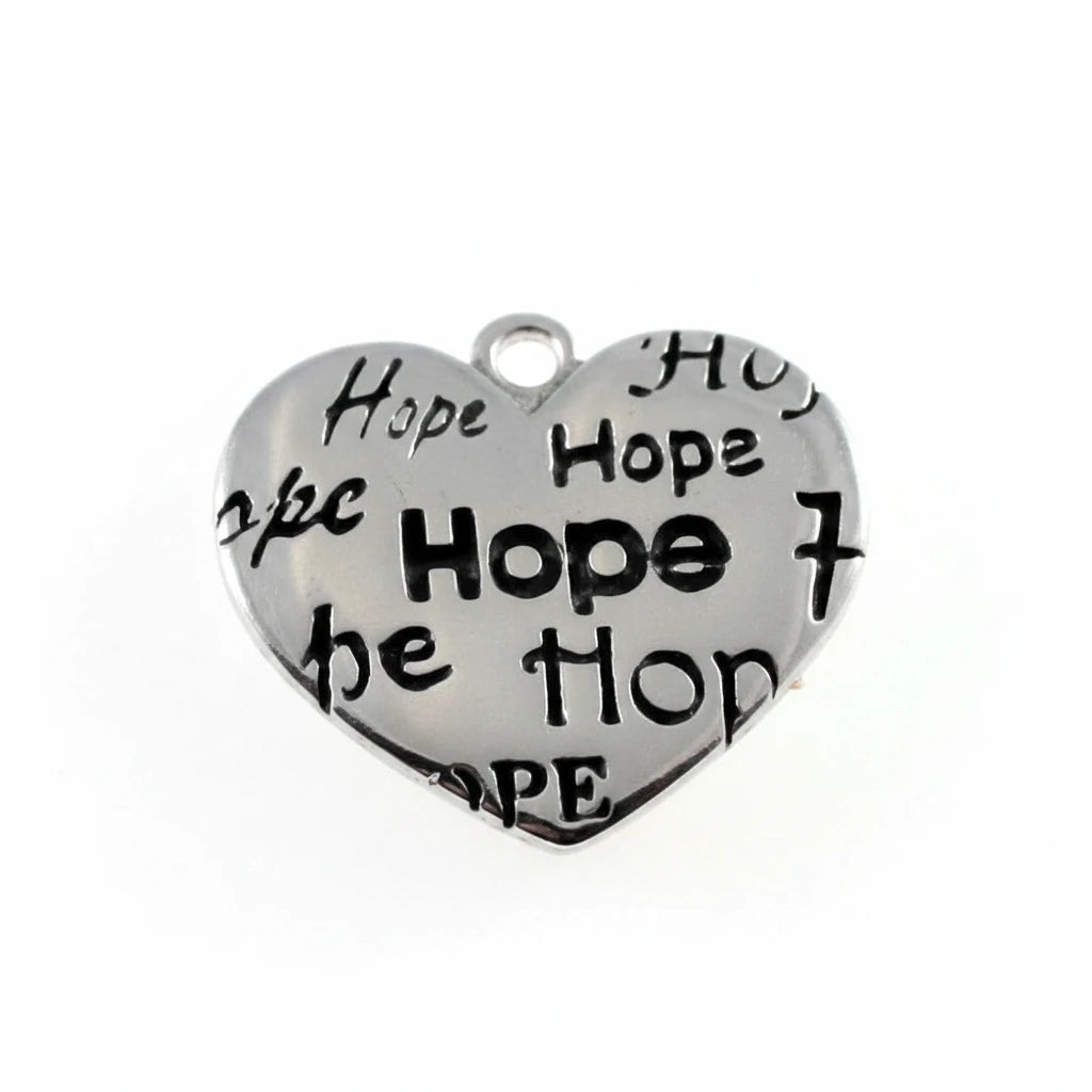 A heart-shaped silver metal charm engraved with the word 'Hope' repeated in black, shown above a millimeter ruler for scale on a white background.