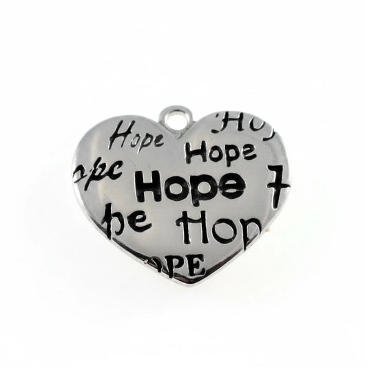 A heart-shaped silver metal charm engraved with the word 'Hope' repeated in black, shown above a millimeter ruler for scale on a white background.