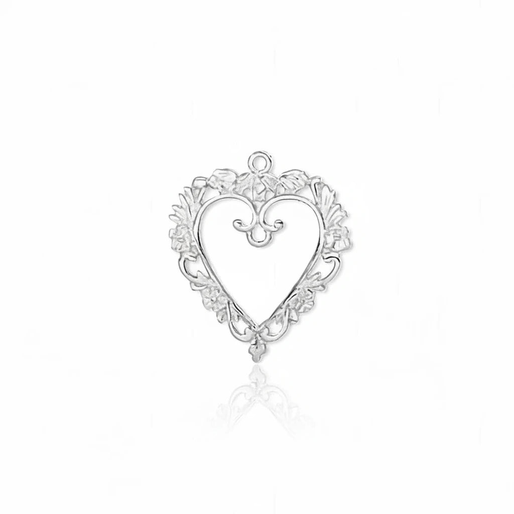 A silver heart-shaped ornamental jewelry charm with a decorative filigree border and a small top loop, shown on a plain white background.