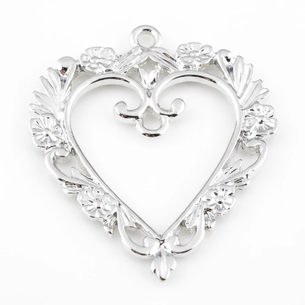 Silver heart-shaped jewelry pendant with an ornate filigree border, floral details, and a top loop, shown on a plain white background.