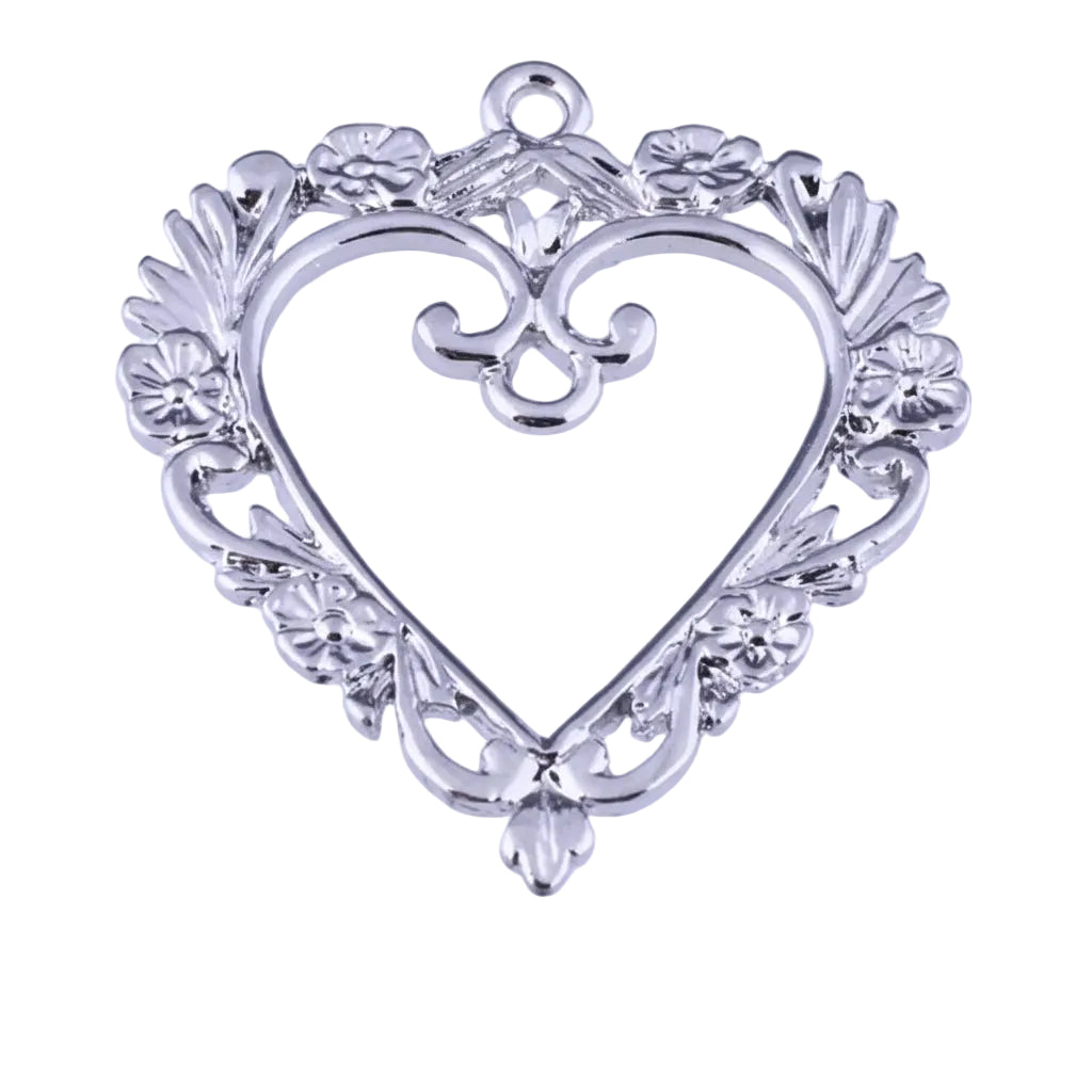 A silver heart-shaped jewelry pendant or charm with ornate filigree and floral details, shown against a white background with a ruler at the bottom indicating scale.
