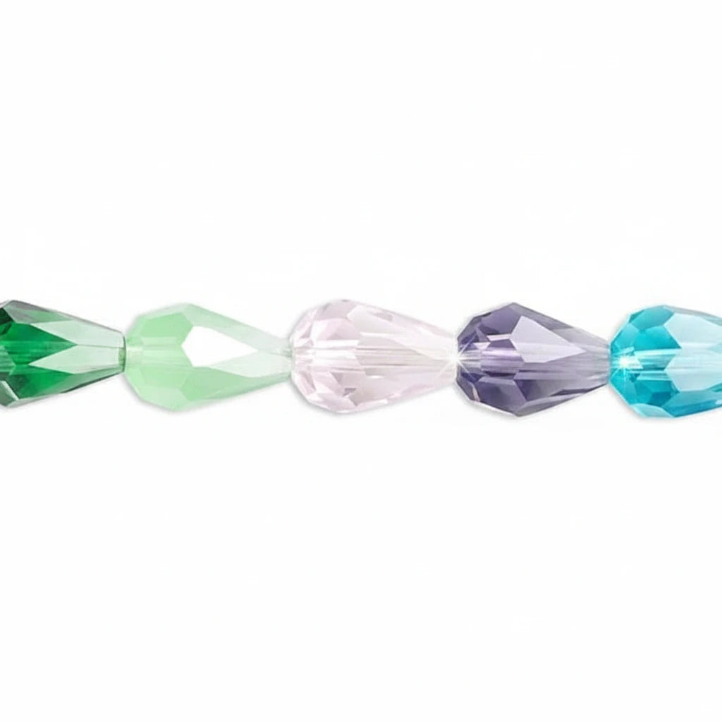 A close-up of faceted crystal beads in green, light green, iridescent white, lavender purple, and turquoise blue, arranged horizontally on a plain white background.