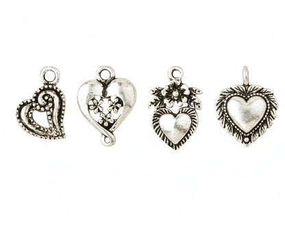Four antique silver heart-shaped jewelry charms with intricate filigree and floral details, arranged horizontally on a plain white background.