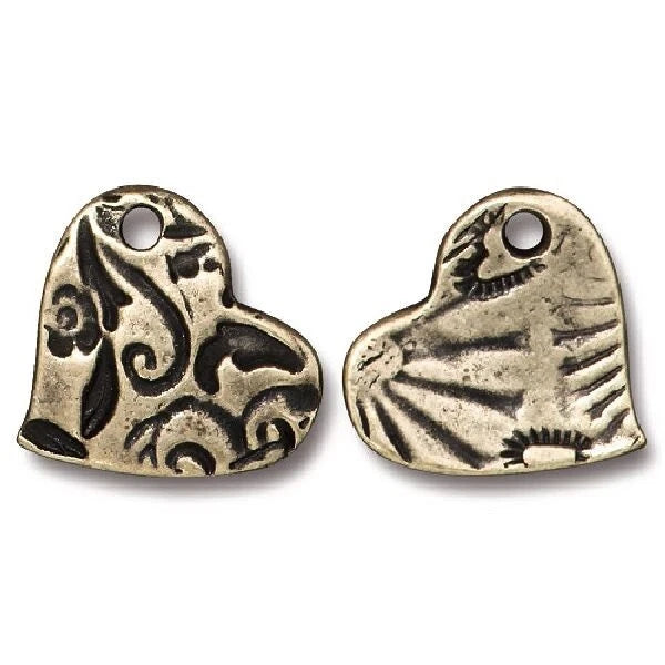Two heart-shaped metal charms with engraved floral and sunburst patterns, shown on a plain white background.