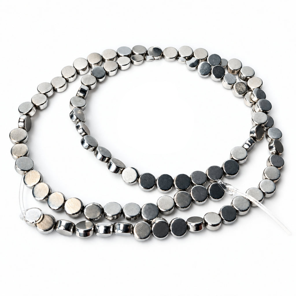 A strand of small round silver beads with polished metallic finishes, coiled on a plain white background.
