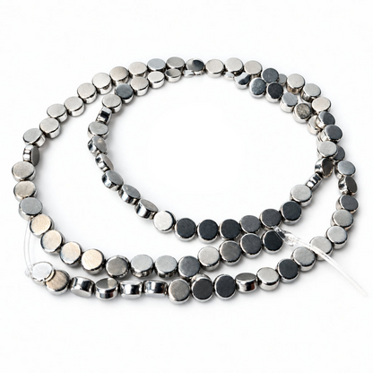 A strand of small round silver beads with polished metallic finishes, coiled on a plain white background.