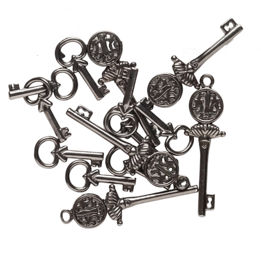 A pile of antique-style metal key charms with ornate circular medallions and decorative heads, arranged on a plain white background.