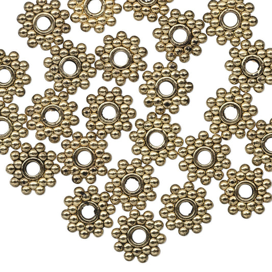 A pile of antique bronze flower-shaped metal findings with a central hole, arranged on a plain white background.