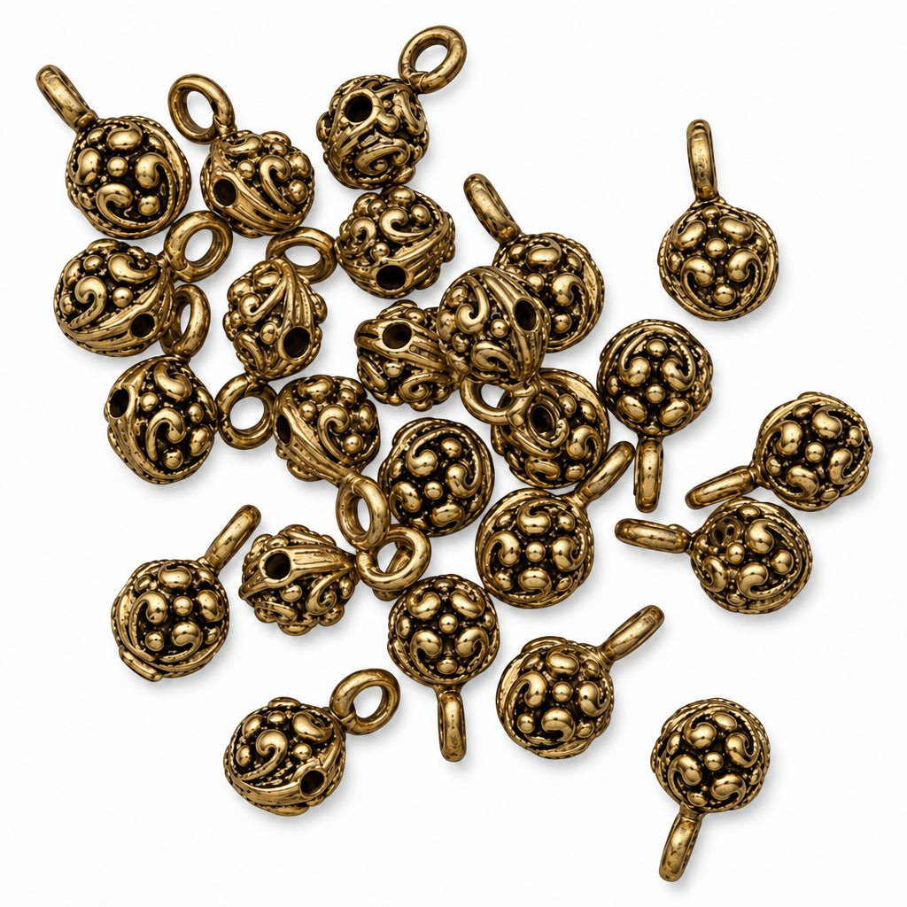 A pile of small antique gold-toned metal charms with loop tops, shown on a plain white background.