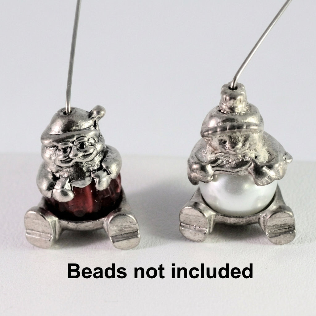 Two small silver-toned hanging ornaments shaped like seated figures, shown on a plain white background with the text 'Beads not included' at the bottom.