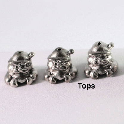 Three small silver-toned metal bead charms shaped like Santa Claus, shown on a plain light background with the word 'Tops' printed at the bottom right.
