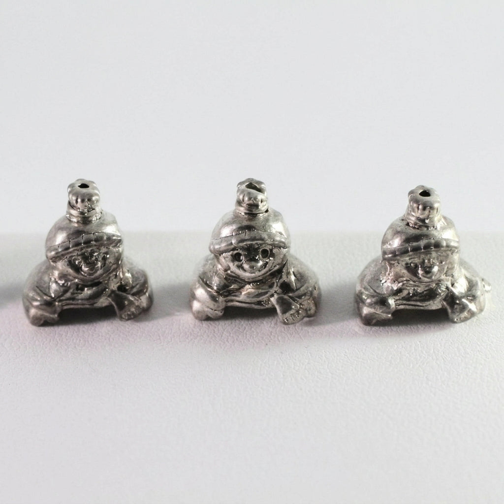 Three small silver frog-shaped beads or charms shown side by side on a plain light background.