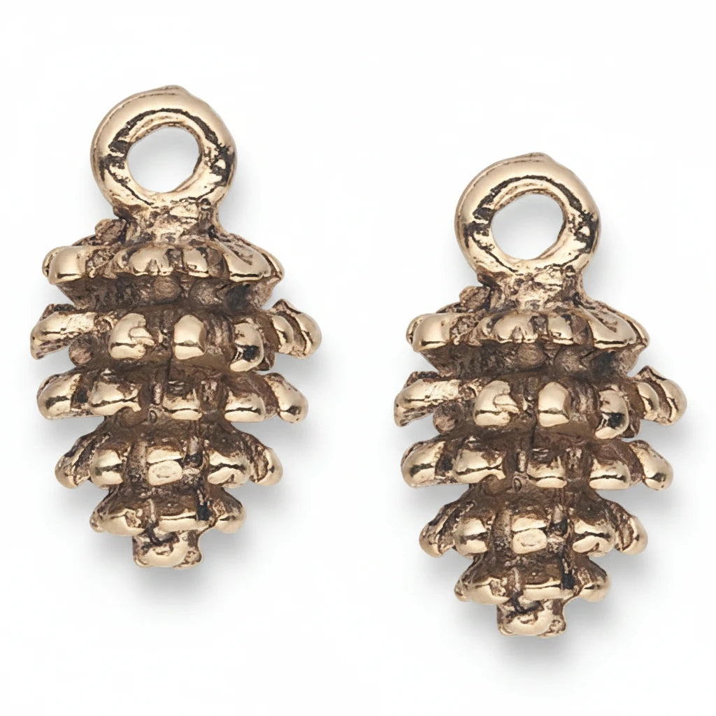 A pair of small metallic pinecone-shaped charms with a textured, oxidized finish and a circular loop at the top, shown on a plain white background.