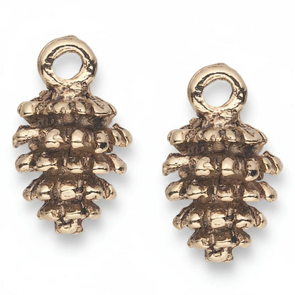 A pair of small metallic pinecone-shaped charms with a textured, oxidized finish and a circular loop at the top, shown on a plain white background.