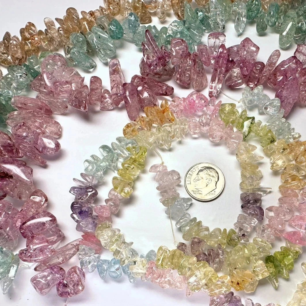 Multicolor raw crystal chip bead strands arranged in circular patterns on a white background, with a US quarter coin in the center for scale.